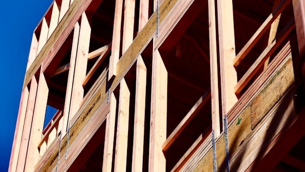 Ossature bois d'une maison neuve en construction, montants et traverses assemblés sous un ciel bleu